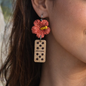 Earring made with beach sand in the shape of a Maga Flower and a domino tile.